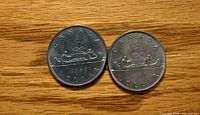 Reverse view of two 1968 Canada dollar coins with Voyageur canoe design