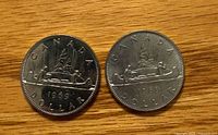 Reverse side of two 1969 Canada dollar coins showing Voyageur design and dates