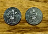 Reverse side of two 1987 Canadian 50-cent coins showing Coat of Arms