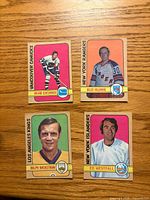 Fronts of four O-Pee-Chee 1972-73 hockey cards laid out on wooden surface