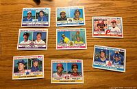 Front view of eight 1983 Topps team leader cards arranged on wooden surface