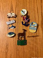 All eight Lions Club lapel pins arranged on wood surface