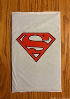 Front of sealed white polybag with red Superman emblem