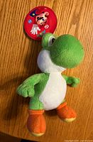 Front view of green Yoshi plush with hangtag
