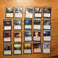 All twenty Magic: The Gathering cards laid out face-up on wooden surface