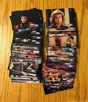 Two stacks of assorted Star Trek The Next Generation trading cards on wooden surface