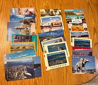 Spread of approximately 35 assorted postcards laid out on floor showing variety of scenic and travel images