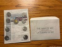 Front view showing sealed 9-coin sheet beside outer sleeve
