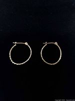 Pair of gold hoop earrings on dark background
