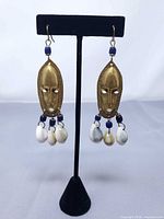 Front view of both mask earrings on stand