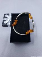 Bracelet on black gift box showing amber chips and textured silver-tone tubes