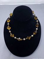 Full view of amber and pearlized bead necklace on display bust