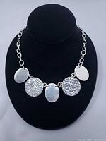 Full view of necklace on bust showing chain and five discs