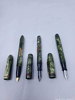 All three fountain pens disassembled showing barrels, caps and nibs