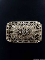 Front view of rectangular gold-tone filigree brooch with rhinestones