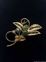 Front view of gold filigree brooch showing jade buds and leaf detail