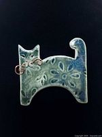 Front view of ceramic cat brooch showing glaze color and copper whiskers