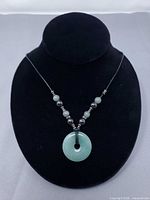 Full view of jade disc pendant necklace on display bust