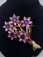 Front view of brooch showing five enamel flowers with purple stones