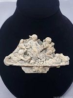 Front view of ceramic brooch showing cherub scene
