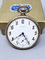 Front view of gold-filled Longines pocket watch against gift box background