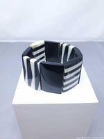 Bracelet displayed upright on white box showing alternating panel design