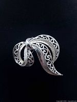 Front view of silver-tone filigree bow brooch