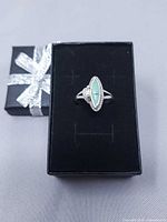 Top view of silver ring with turquoise stone on black box