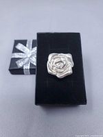 Top view of silver coloured rose-form ring on gift box