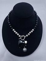 Full view of necklace on display bust showing bead pattern and dangling charms