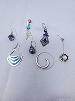 All seven single earrings laid out on fabric