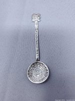 Full view of sterling silver souvenir spoon showing bowl, handle décor, finial