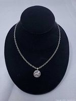 Necklace with round pendant displayed on bust