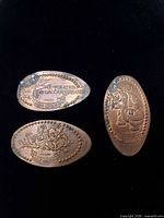 Front of three elongated Disney souvenir pennies showing Pirates of the Caribbean, Figment and Dumbo designs