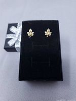 Front view of maple leaf earrings on black box lid