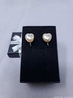 Front view of heart-shaped pearlized earrings in box