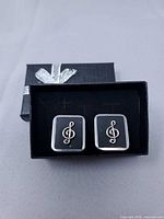 Front view of both earrings in box showing treble clef design