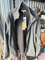 Full view of dark grey fleece sweater on hanger showing front zipper, collar and pockets