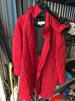 Front view of red Calvin Klein quilted jacket showing zip front, pockets, hood with faux fur trim