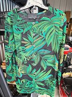Front view of Carole Little green leaf print blouse on hanger