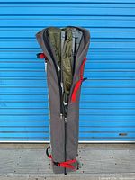 Shelter folded inside grey wheeled zippered bag with red straps
