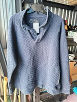 Front view of navy quilted pullover hanging