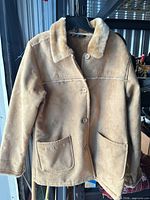 Full front view of tan faux suede shearling jacket on hanger