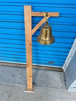 Full view of brass bell mounted on pine stand
