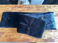 Full view of black faux fur scarf showing fur side and quilted lining