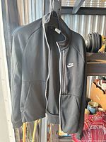 Front view of black Nike zip-up sweater on hanger