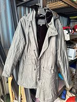 Full view of grey Novelti hooded parka coat hanging, showing exterior design and length