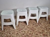 four white plastic stools lined up side by side