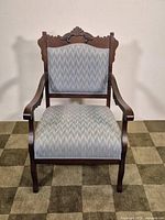 Full front view of carved wood armchair with patterned upholstery