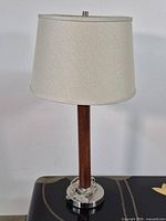 Full view of lamp showing wood pole, metal base and fabric shade